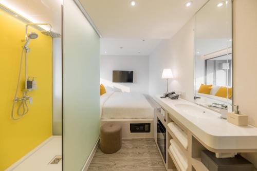 曼谷Yello Rooms Hotel Victory Monument的浴室设有1张床、2个盥洗池和淋浴。