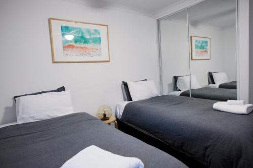 巴瑟尔顿FortyTwo - Oceanside Retreat Busselton的一间卧室配有两张床和镜子