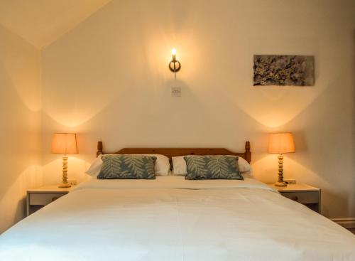 尼纳The Waterside Cottages的一间卧室配有一张带两盏灯的大型白色床。