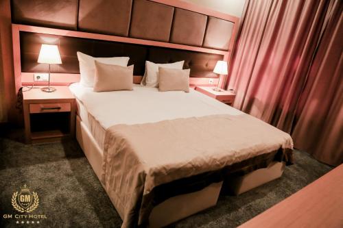 巴库GM City Hotel的一间卧室配有一张大床、两张桌子和两盏灯。