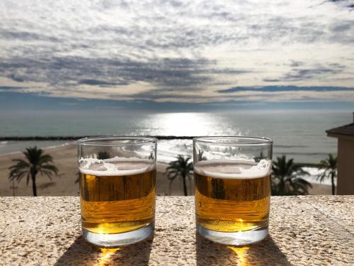 库尼特Espectacular ático dúplex con vistas al mar的两杯啤酒坐在海滩附近的桌子上