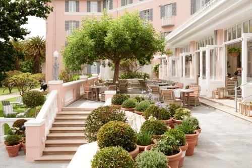 开普敦Mount Nelson, A Belmond Hotel, Cape Town的庭院配有桌椅和盆栽植物