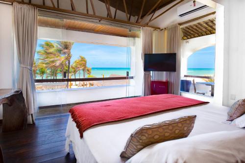 卡姆布库Vila Coqueiros Boutique Hotel的一间卧室设有一张大床,享有海景