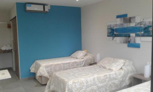 罗卡将军市Hotel El Recreo的一间设有两张床和蓝色墙壁的客房
