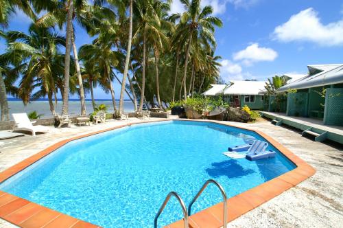 拉罗汤加日天堂海滩简易别墅酒店的一座棕榈树游泳池和一座房子