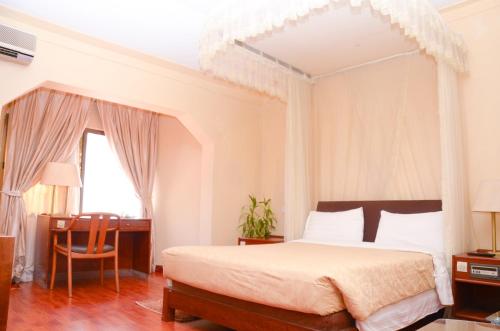 坎帕拉Fang Fang Hotel的一间卧室配有一张大床和一张书桌