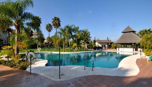 EsteponaEl Campanario del Paraíso的棕榈树度假村的游泳池和凉亭