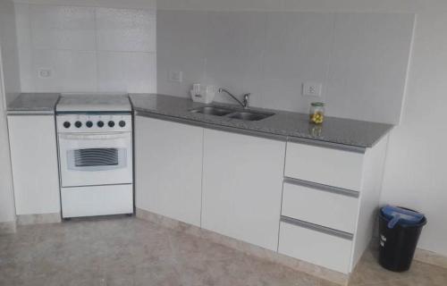 布兰卡港Bahiaxdia Saavedra的白色的厨房设有水槽和炉灶。