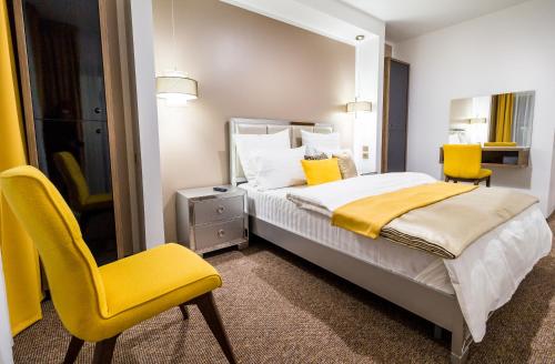 锡比乌Dumbrava Residence的一间卧室配有一张床和两张黄色椅子