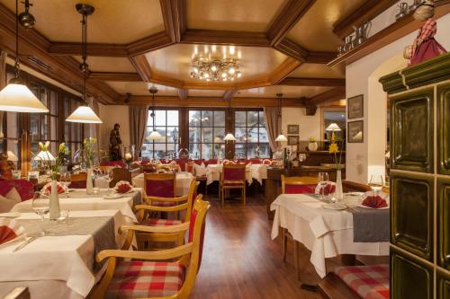 巴特彼得斯塔尔弗莱尔阿德勒酒店 的餐厅配有白色的桌椅和吊灯