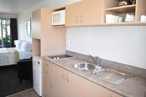 芒格努伊山海岸救生队汽车旅馆 的一个带水槽的厨房和一张位于客房内的床