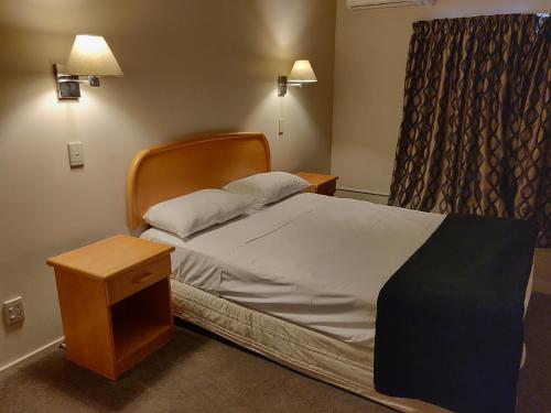 奥克兰瑞兰埃普索姆汽车旅馆的一间卧室配有一张床、床头柜和窗户