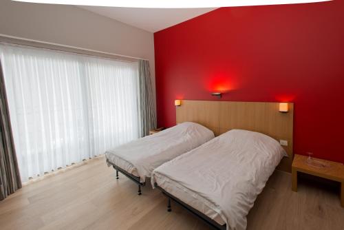赫伦塔尔斯Hotel De Zalm的一间卧室设有红色的墙壁和两张床