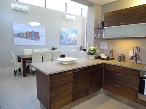 豪特湾Chapman's Peak Penthouse的厨房配有木制橱柜和一张带白色椅子的桌子。