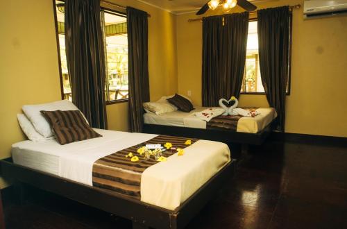 帕拉马里博Overbridge River Resort的两张位于酒店客房的床,上面有鲜花