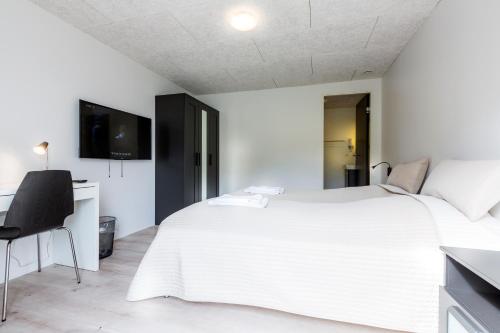 Við Gjógv吉雅加杜尔乔夫宾馆的白色的卧室配有一张白色的大床和一张书桌