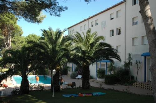 莱斯卡拉Apartamento MAGDA PARK J-2E的一座棕榈树环绕的建筑,位于游泳池前