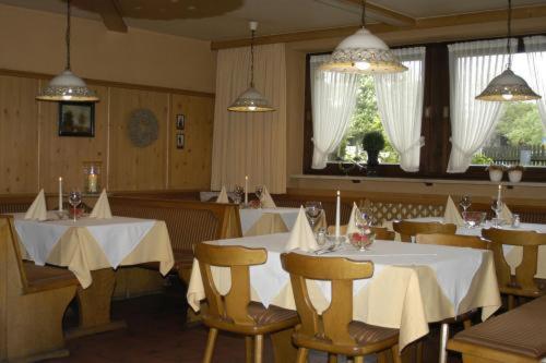 劳布灵克里尔尔酒店的餐厅设有白色的桌椅和窗户。