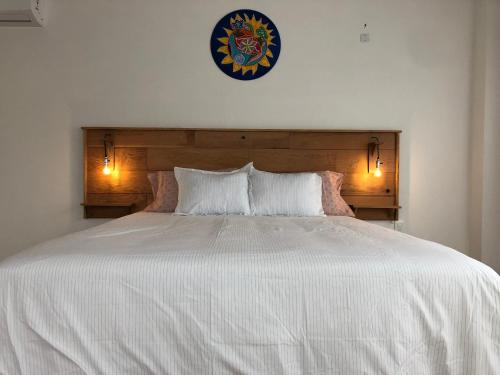 埃斯特角城Las grutas Punta del este的一张带两个枕头的大白色床和墙上的时钟