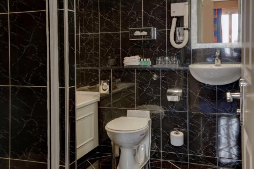 彼得伯勒The Bull Hotel; Sure Hotel Collection by Best Western的黑色瓷砖浴室设有卫生间和水槽
