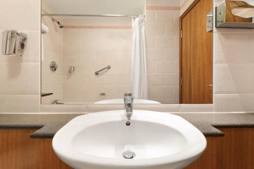 希灵登Savera Hotel South Ruislip的浴室配有白色水槽和浴缸。