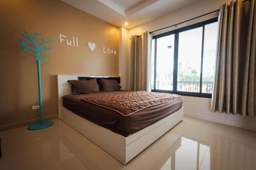 华欣FullLove HuaHin PoolVilla的卧室配有一张床铺,墙上挂着一棵树