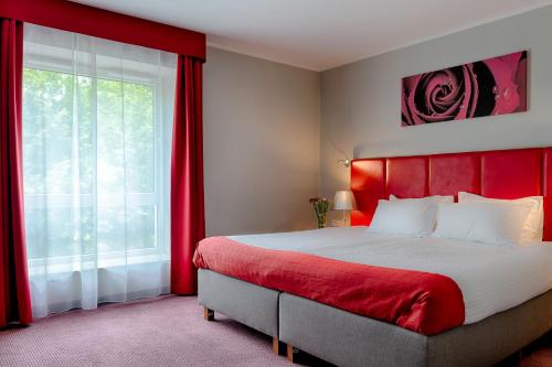 霍茹夫福克斯卡托维兹霍茹夫酒店的一间卧室配有一张带红色床头板的床和窗户