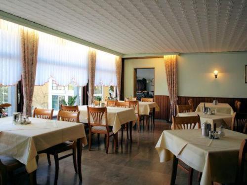 巴特萨克萨乌苏拉酒店-膳食公寓的用餐室配有桌椅和白色桌布