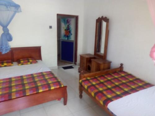 卡特勒格默Dinesh Guest House的带两张床和镜子的客房