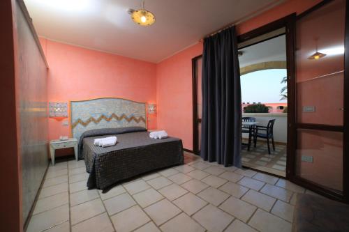 普罗斯西托角Villaggio Punta Grossa的一间卧室配有一张床,阳台配有桌子