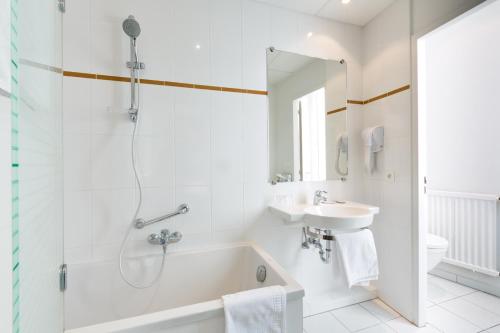 斯特拉斯堡文多姆酒店的白色的浴室设有浴缸和水槽。