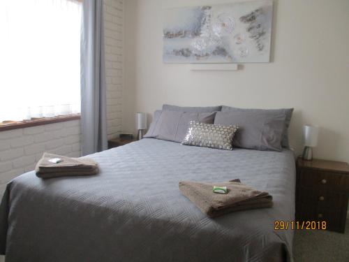 梅林布拉海港之光假日公寓的一间卧室配有一张床,上面有两条毛巾