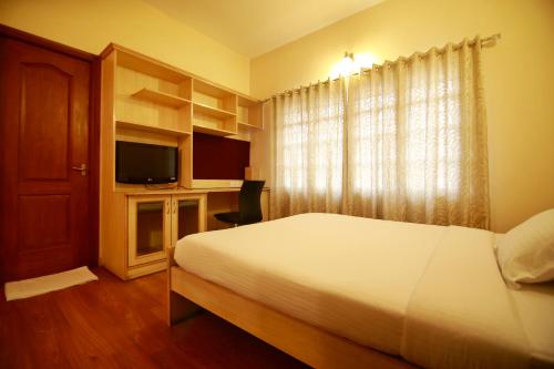 班加罗尔Falcon Suites Residency Road的一间卧室配有一张床和一张书桌及电视