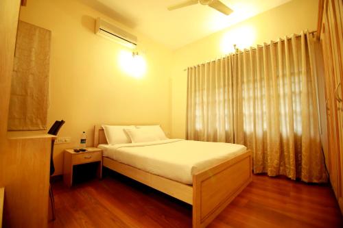 班加罗尔Falcon Suites Residency Road的一间卧室配有一张带白色床单的床和一扇窗户。