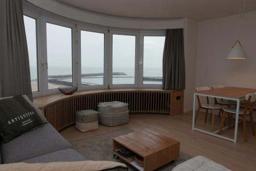 奥斯坦德Appartement met Zeezicht的带沙发、桌子和窗户的客厅