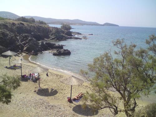 菲尼卡斯Villa Annita, with extraordinary view near the sea的沙滩上,有遮阳伞,有人躺在沙滩上