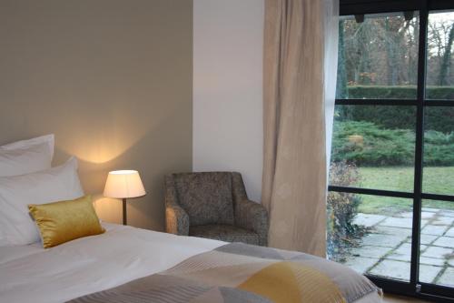 拉莫赫莱Les Enclos Bed and Breakfast à 4 mn de Chantilly的卧室配有床、椅子和窗户。