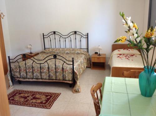 奥特朗托La Pineta Residence的一间卧室设有两张床和一张花瓶桌子。