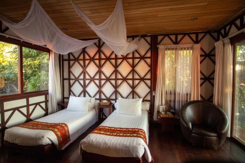 娘瑞观景点生态住宿度假村的一间卧室设有两张床、一把椅子和窗户。