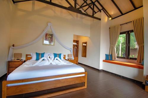 特鲁克巴库民丹岛别墅海滩温泉度假酒店的卧室配有带蓝色枕头的大型白色床