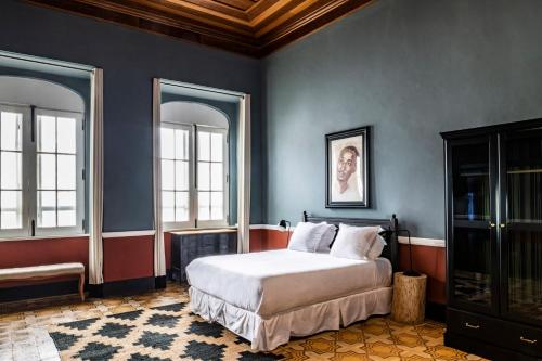 Santo AntónioHotel Roça Sundy的一间卧室设有一张床和两个窗户。