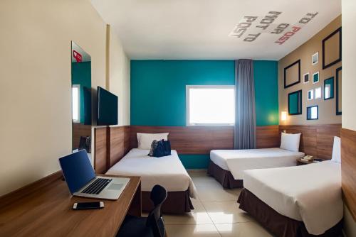 里贝朗普雷托ibis Styles Ribeirao Preto Braz Olaia的酒店客房设有两张床和一张书桌上的笔记本电脑