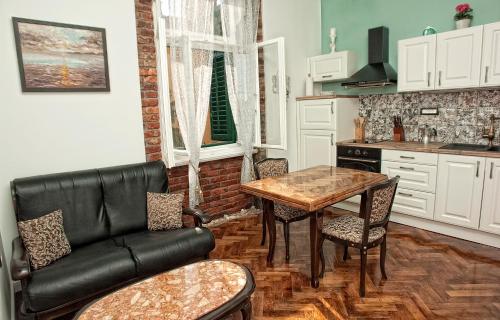 奥帕提亚Apartment Nostalgie的厨房配有桌子和黑色皮沙发