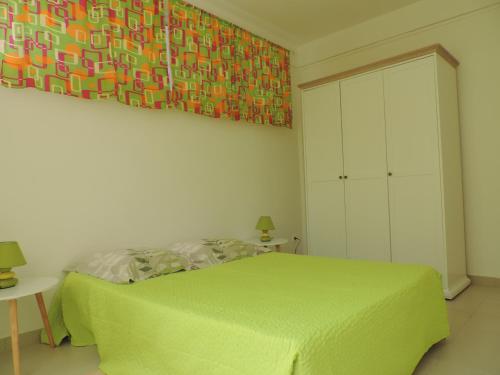 法兰西堡Any's Appart的一间卧室配有一张绿色的床,墙上挂着一幅画