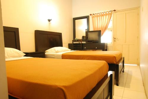 PadangThe Abidin Hotel Syari'ah的酒店客房设有两张床和电视。