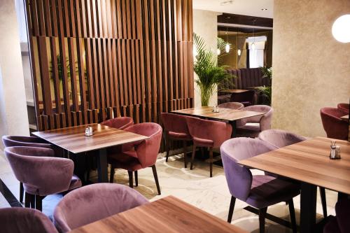 巴尼亚卢卡伊德亚酒店的餐厅设有木桌和紫色椅子