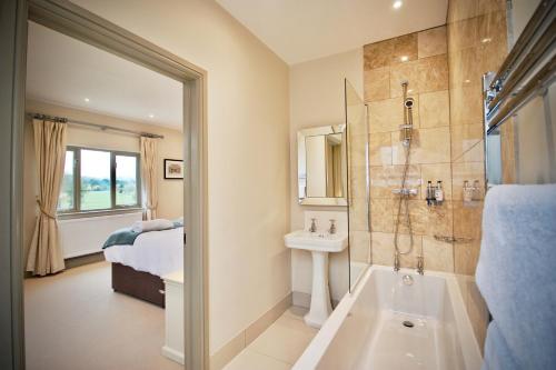 奥尔顿Blacknest Golf and Country Club的带淋浴、盥洗盆和浴缸的浴室