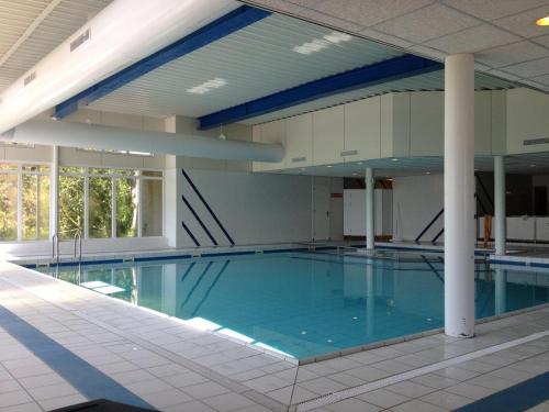 霍勒姆Gezellige App STRANDHUYS en DE VUURTOREN, beg grond met Prive TERRAS -eigen KEUKEN - Incl Verwarmd Binnen ZWEMBAD的大楼内一个蓝色的大型游泳池
