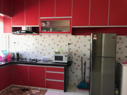 Bagan SeraiSafwa Homestay Bagan Serai的厨房配有红色橱柜和不锈钢冰箱