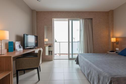 圣佩德罗-德尔皮纳塔尔罗多马spa及海水疗养酒店的酒店客房配有一张床和一张书桌及一台电视
